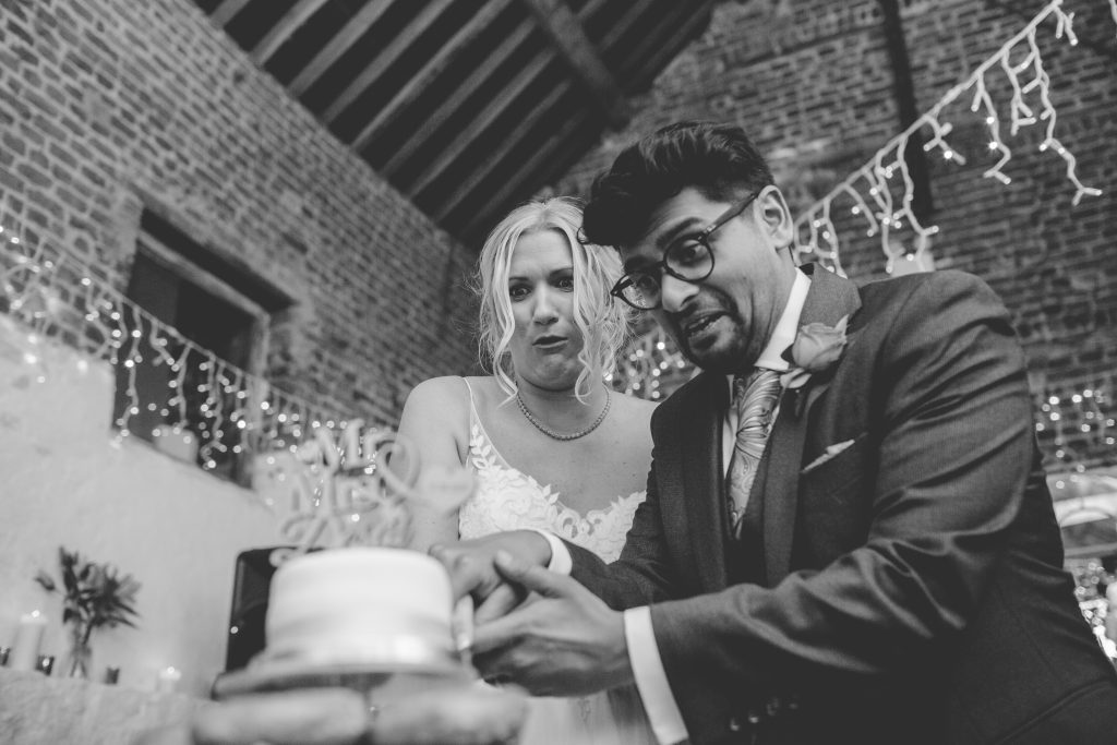 black and white photo of newly weds cutting cake