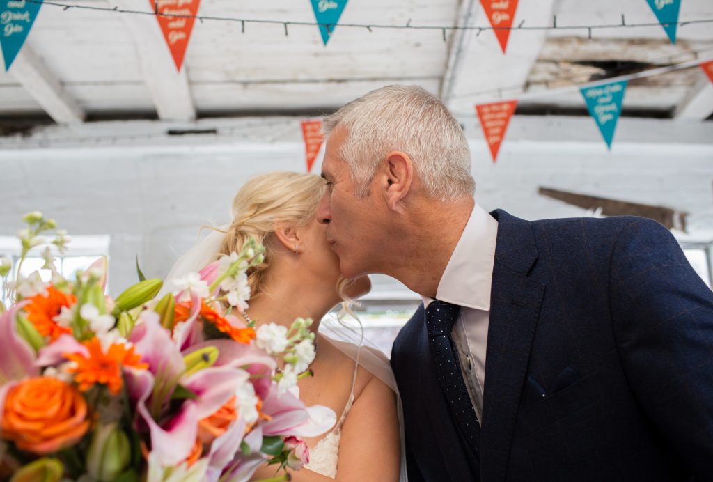 father of bride kissing daughter on cheek